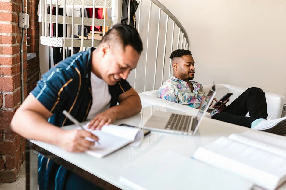 Osoba zapisující si poznámky do diáře u stolu s notebookem.